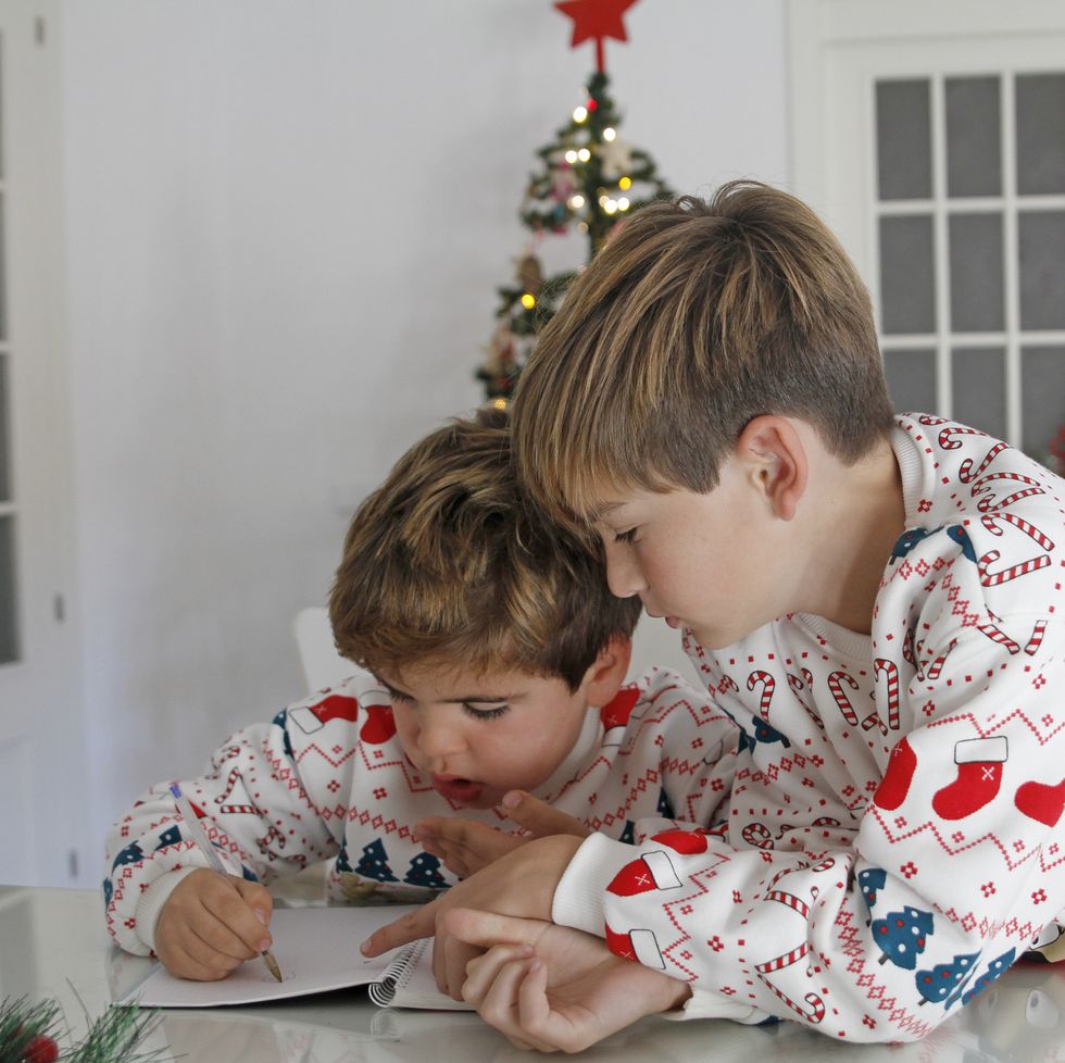 siblings doing homework at home dressed in christmas pajamas