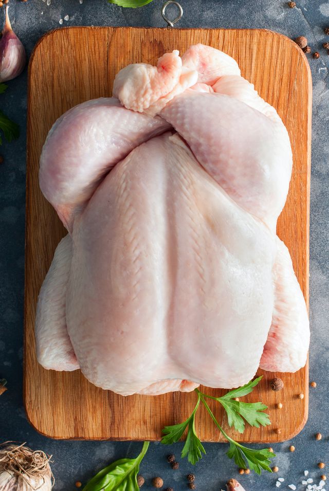 whole raw chicken on a wooden board with spices for cooking, top view, horizontal, copy space