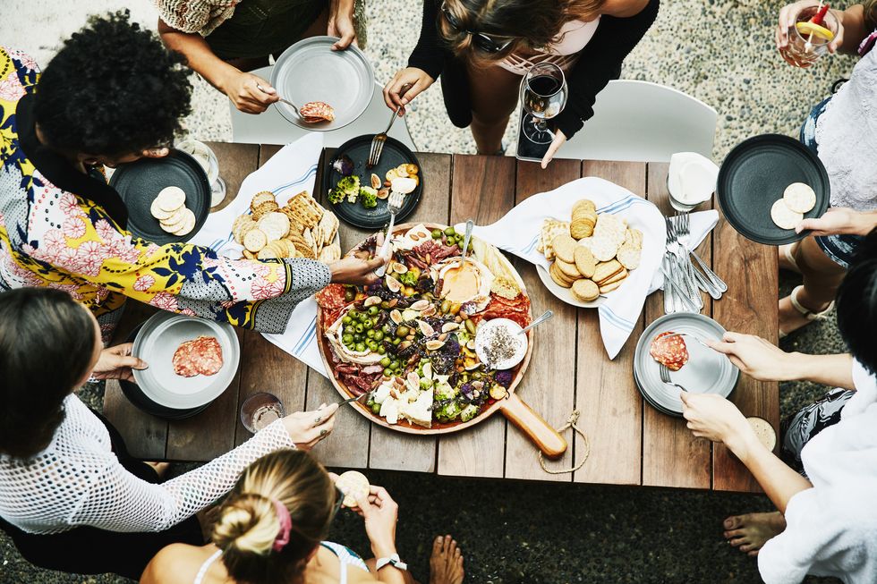 overhead view of group of friends enjoying buffet of food during party