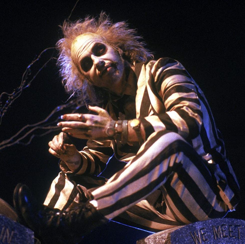 beetlejuice sits in his striped suit in a scene from beetlejuice a good housekeeping pick for best halloween movies