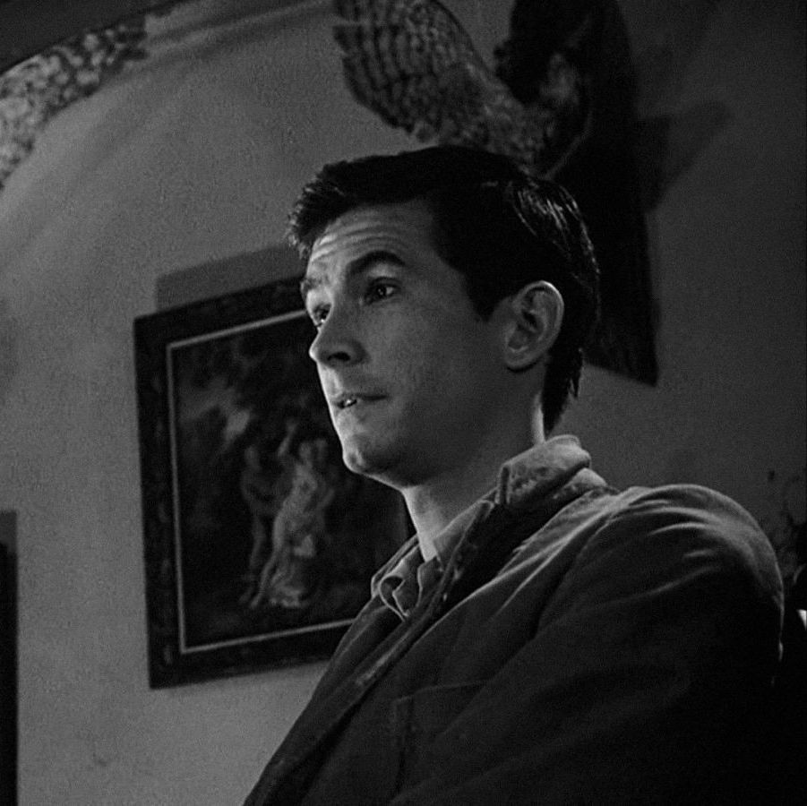 norman bates stands with a slight smile on his face in a scene from psycho, a good housekeeping pick for best halloween movies