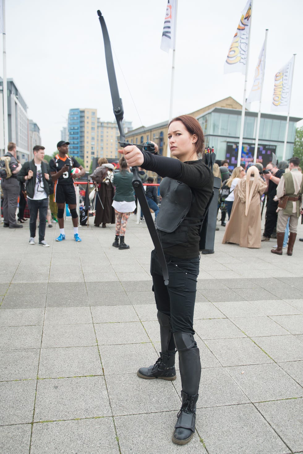 woman dressed in homemade all black katniss everdeen costume with a bow and arrow