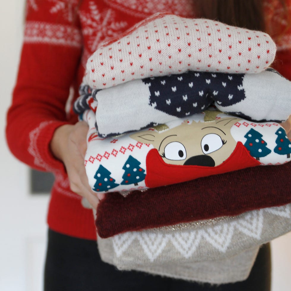 close up of woman holding stack of folded sweaters