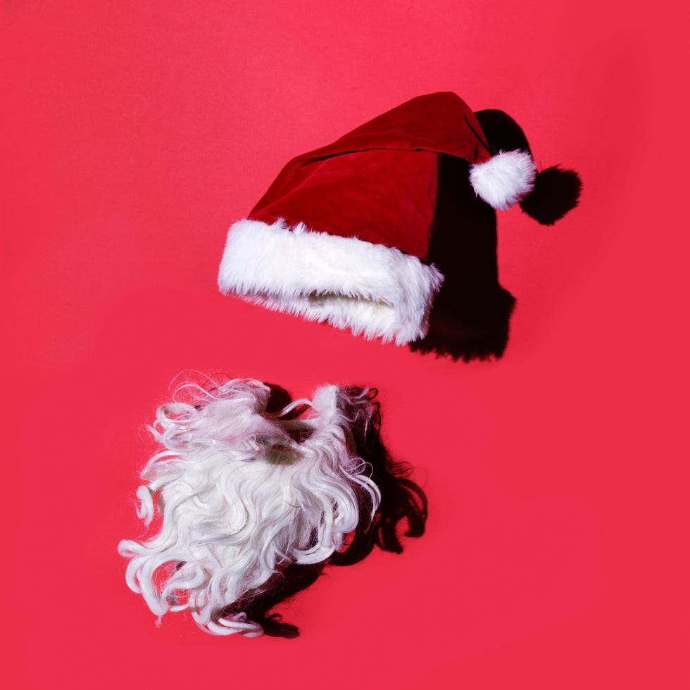 santas red hat and beard photographed on red backdrop