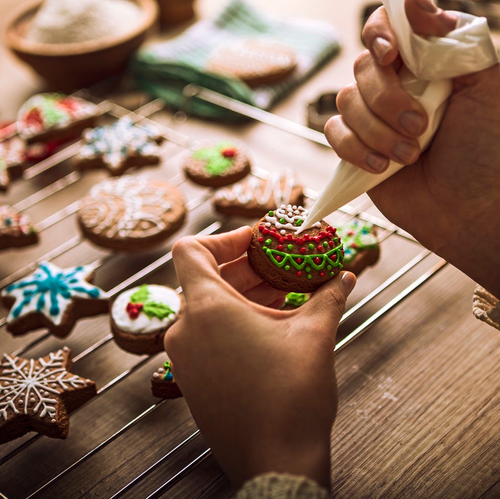 close up of a woman's hands decorating christmas cookies