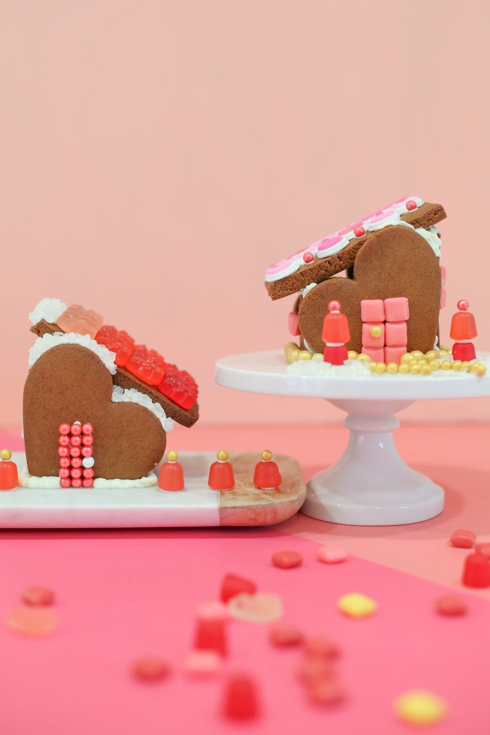 two heartshaped valentines day gingerbread houses decorated in red and pink candy