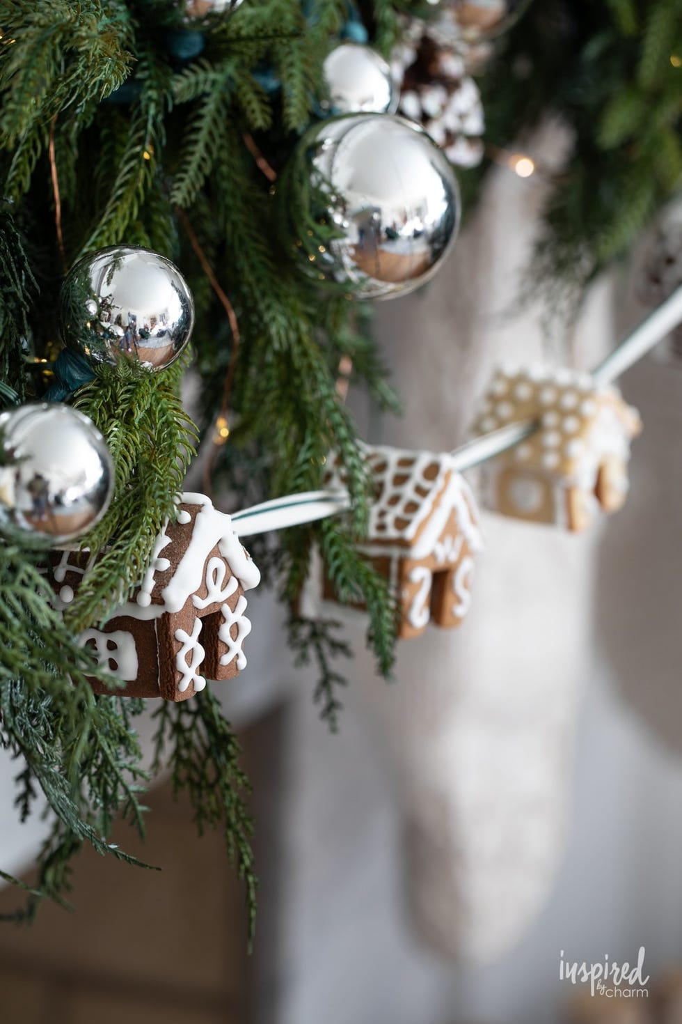 mini gingerbread houses hanging as garland with silver ornaments and green garland