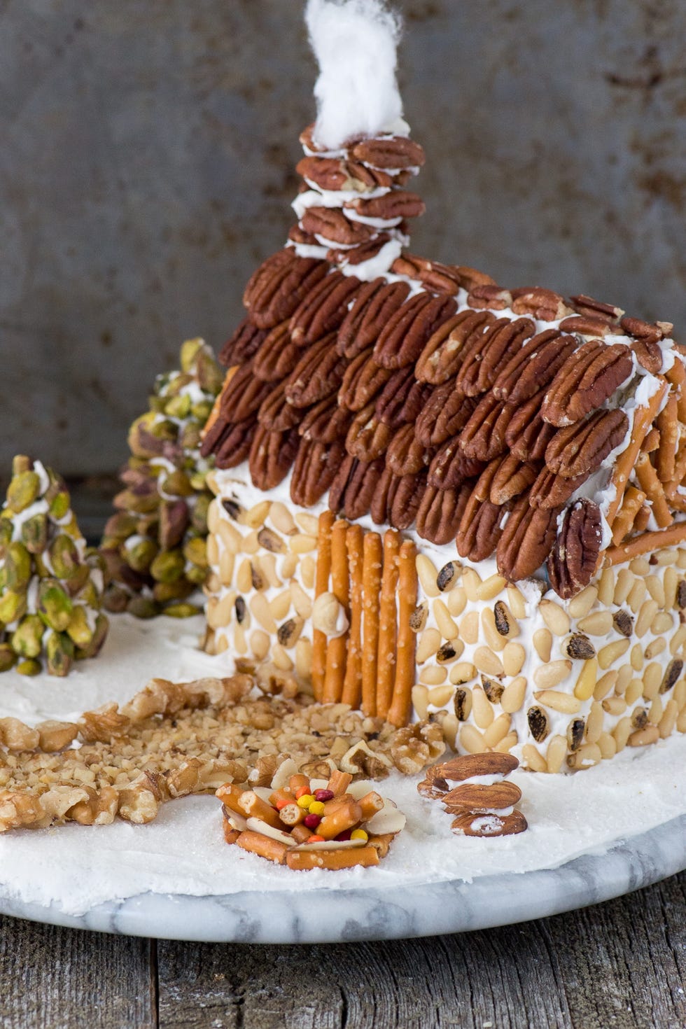 a gingerbread house decorated entirely with nuts and pretzel sticks