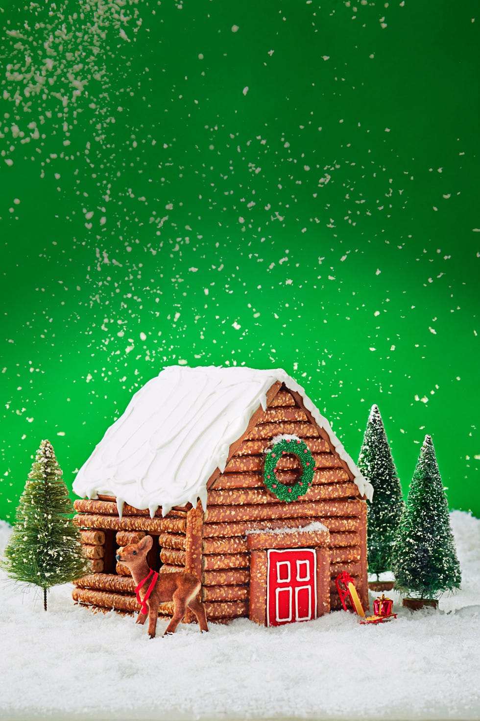 pretzel gingerbread log cabin against a green background