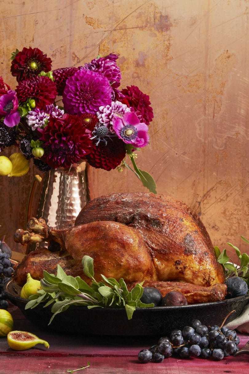 cajun spiced thanksgiving turkey on a platter with a vase of purple flowers in the background