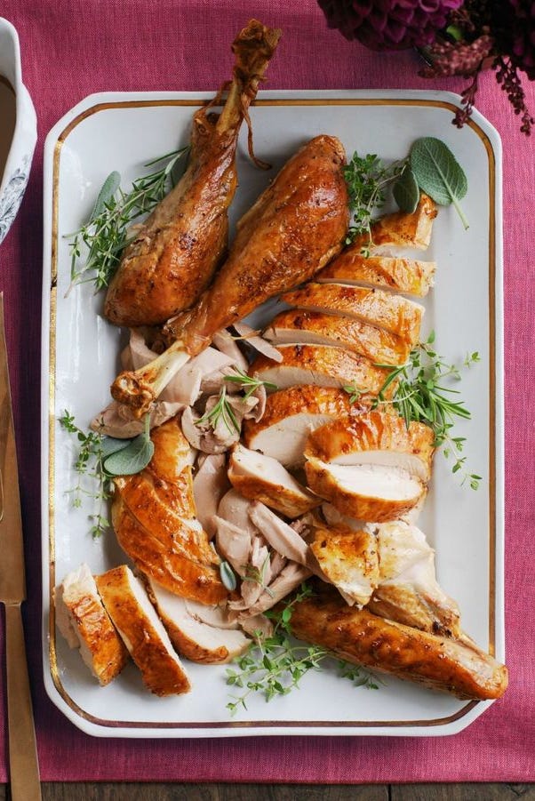 garlic and herb roasted turkey sliced on a white serving platter