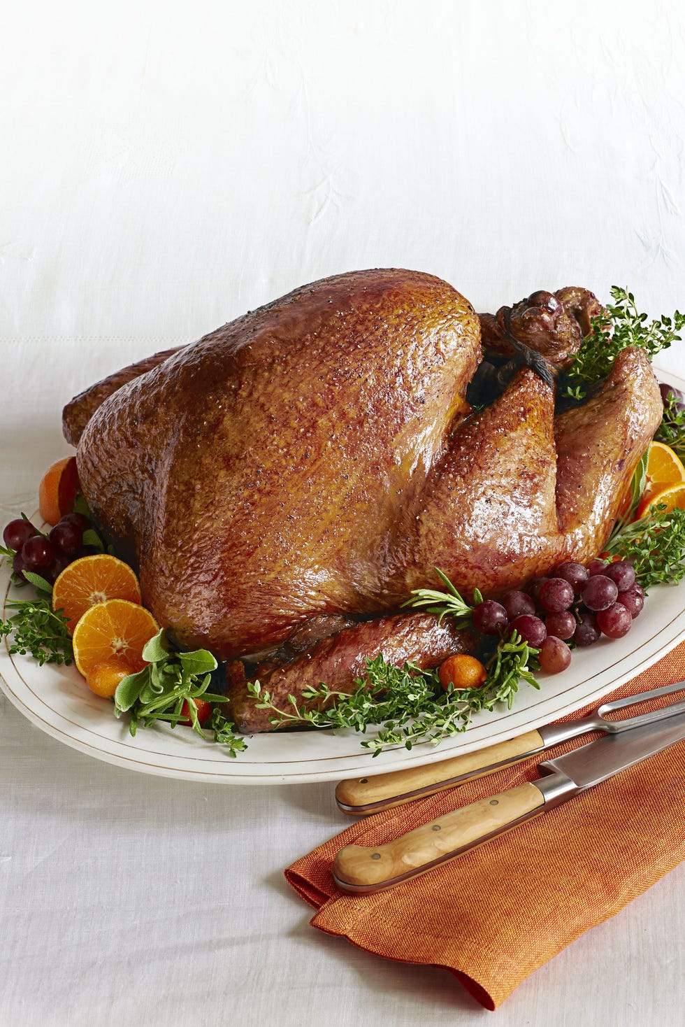 golden roasted turkey on a serving platter with grapes, orange slices, and herbs