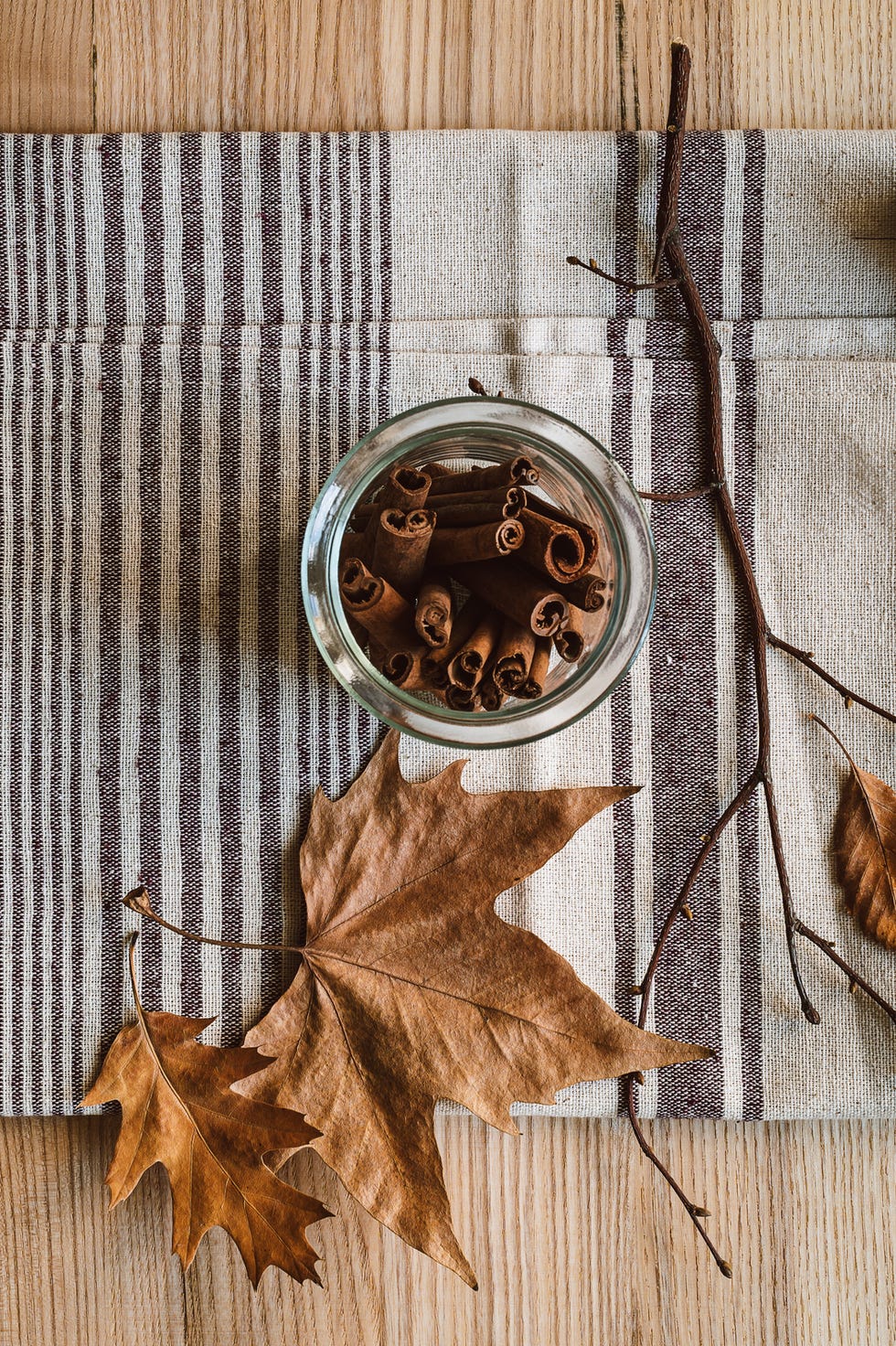 cinnamon sticks in glass jar on linen towel autumn, fall still life