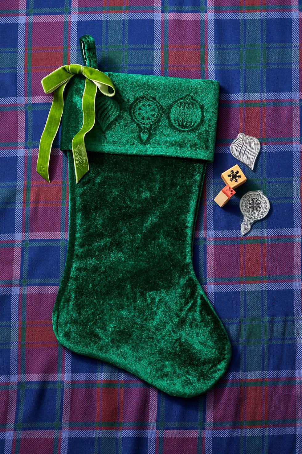 green velvet christmas stocking with ornaments on a plaid background