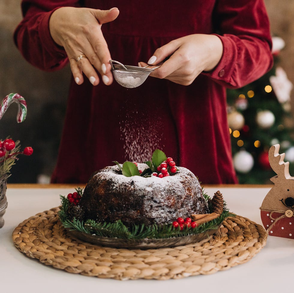 midsection of woman dusting powder sugar on cake