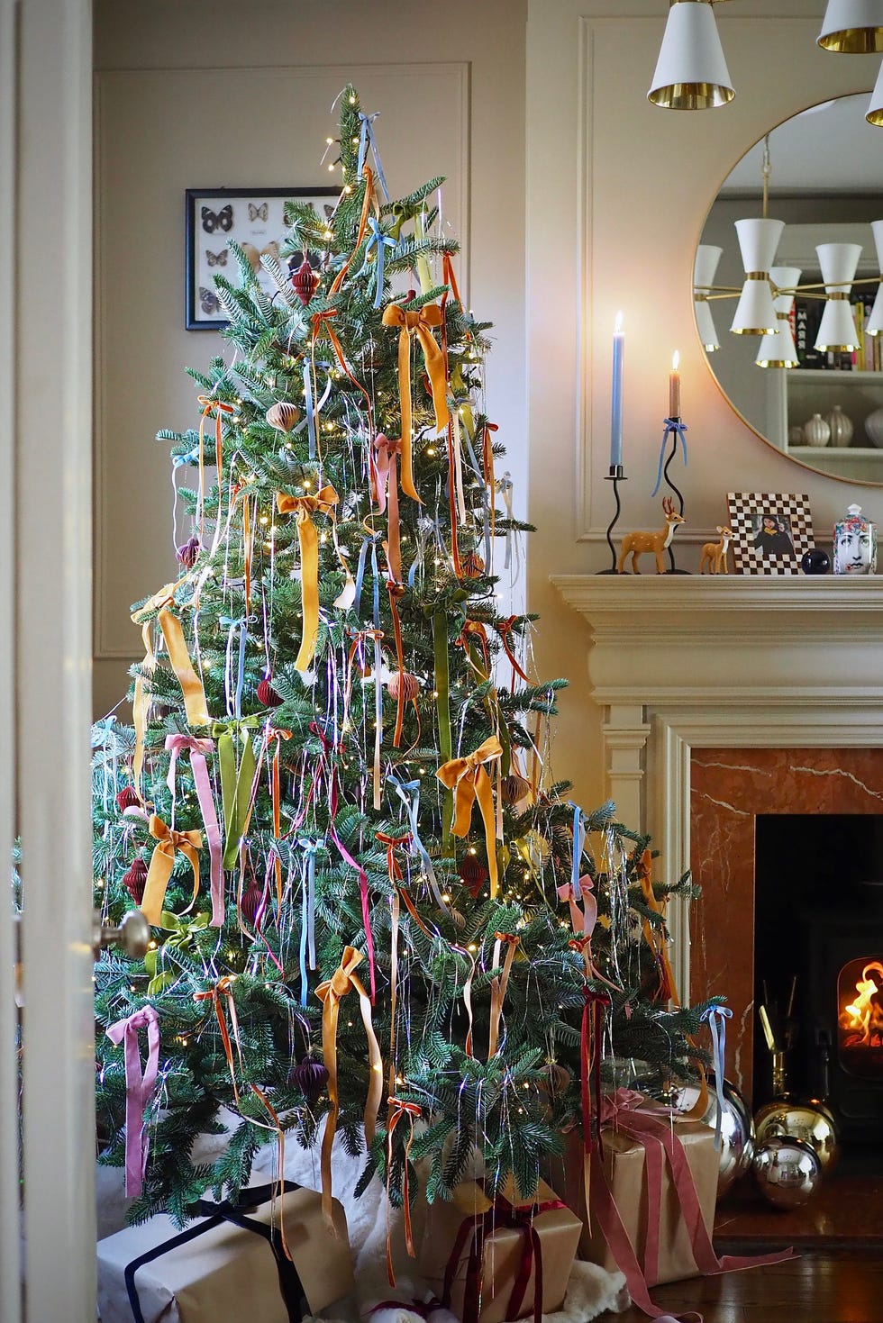 christmas decorating design trends, decorated christmas tree with ribbons and ornaments in a cozy living room