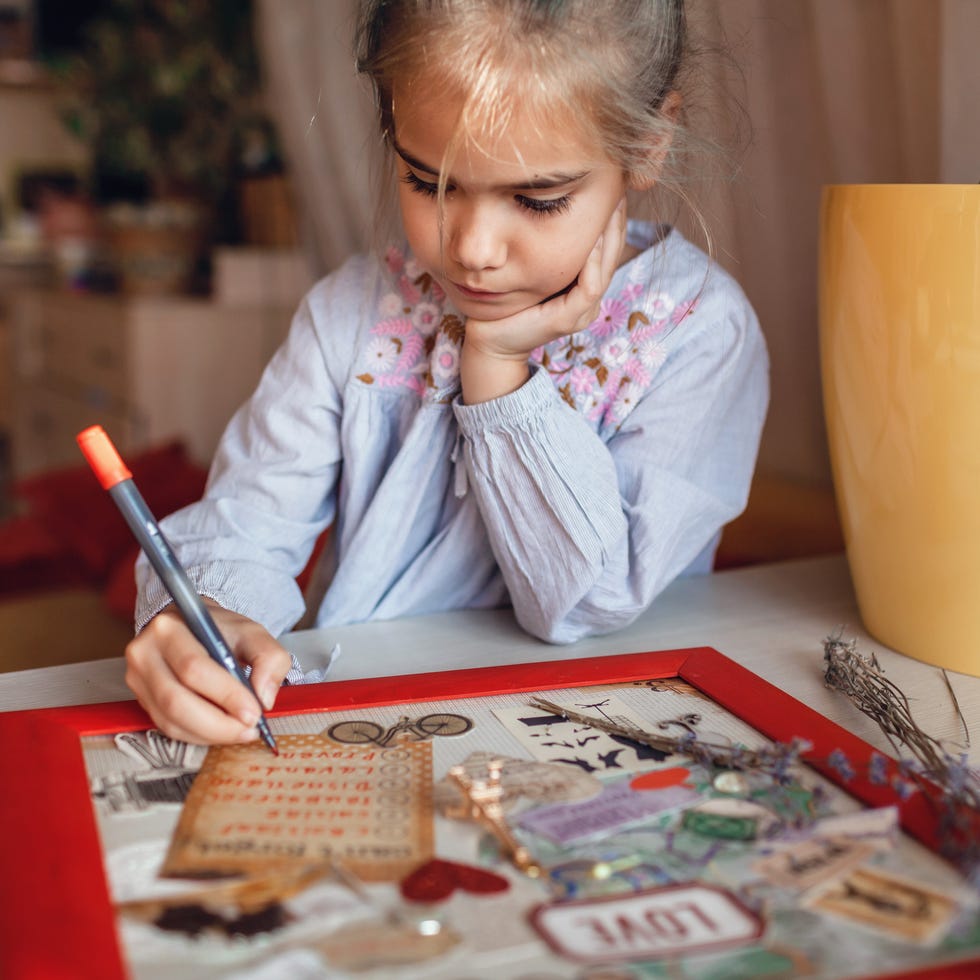 cute girl dreaming about travel to france and creating mood board with sheets of paper, pictures and words