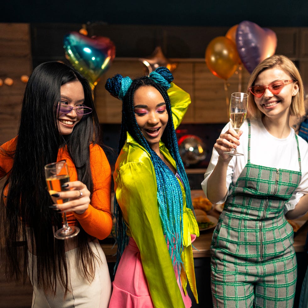 young women and men celebrating in the apartment drinking and eating, dancing and having fun