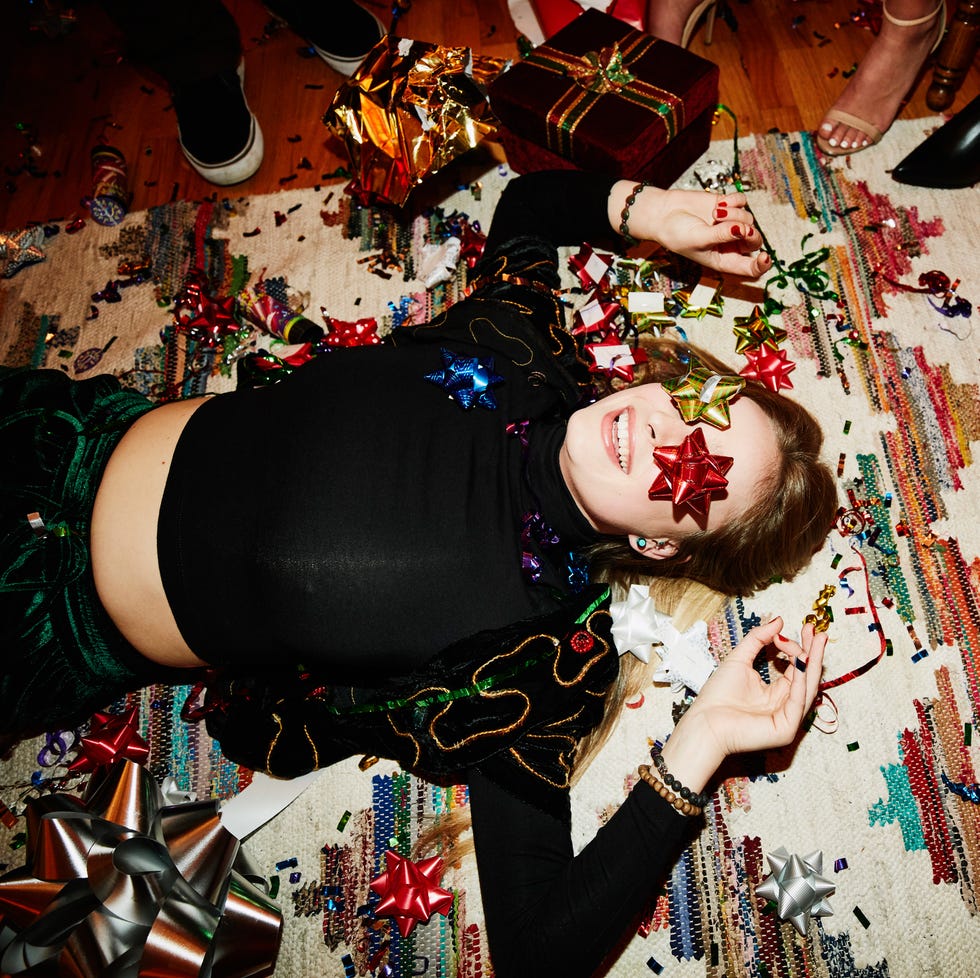 laughing woman lying on floor with bows over eyes during holiday party with friends