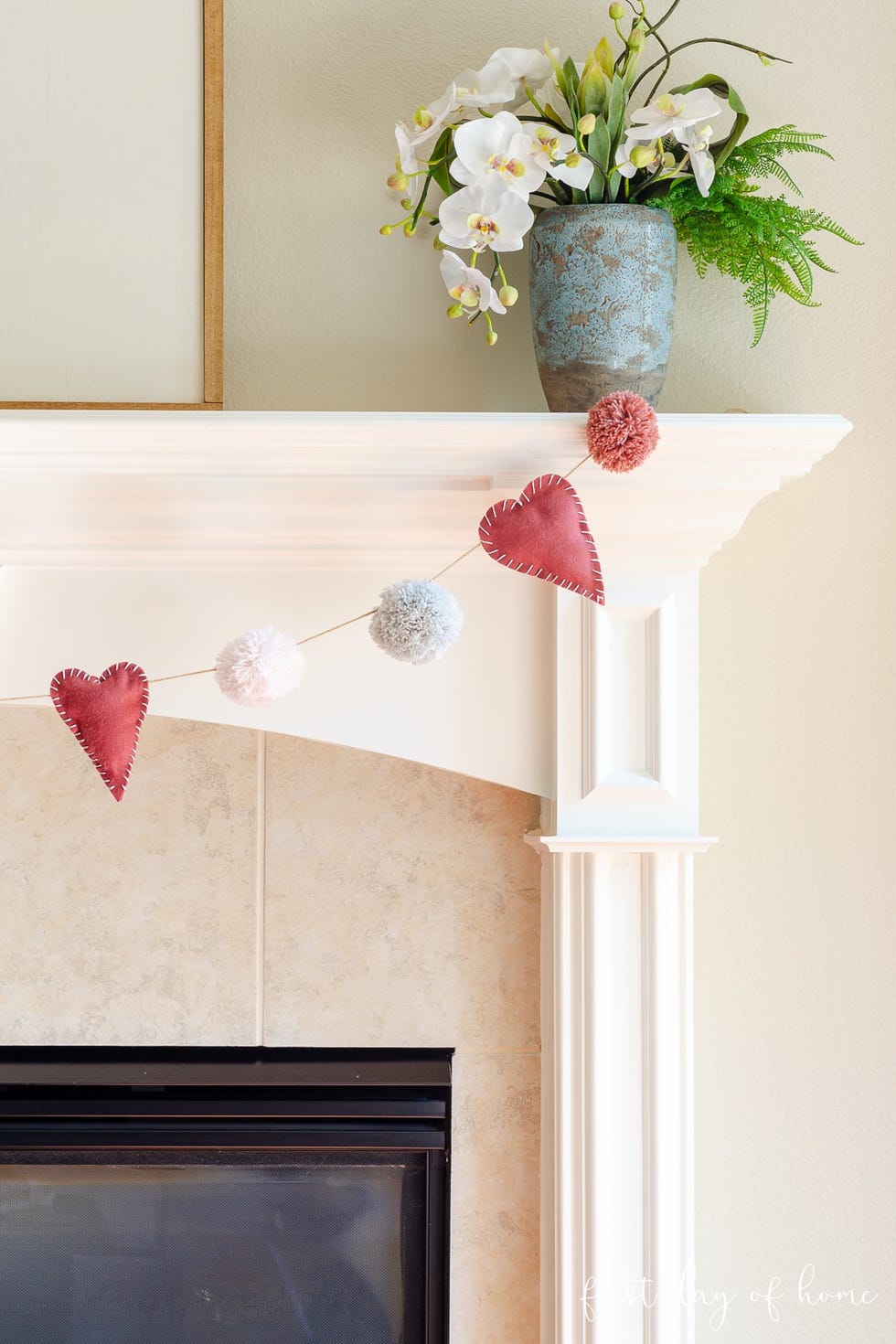 decorative mantel featuring a floral arrangement and a garland of hearts and pompoms