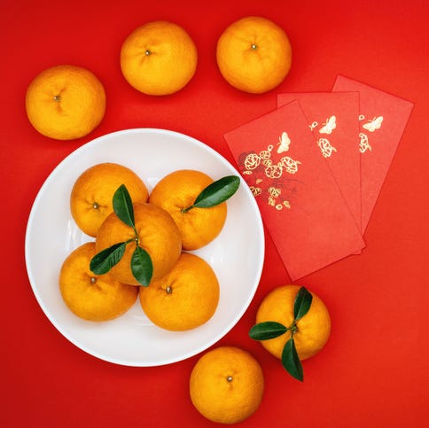 whole tangerines on white plate with red background