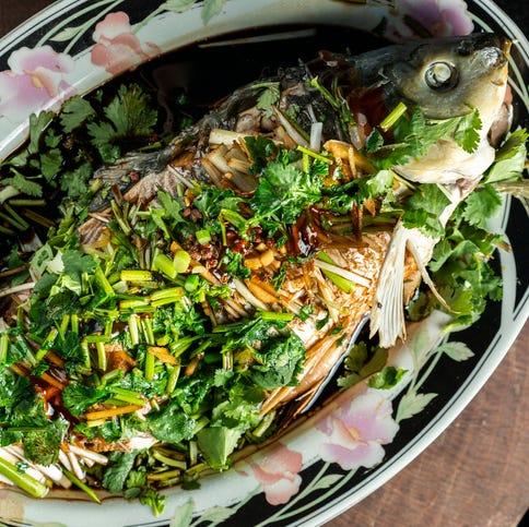 grilled whole fish with herbs on ornate plate