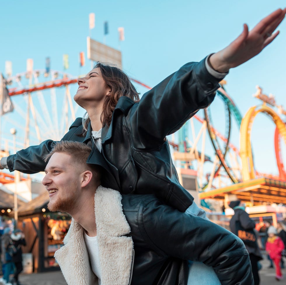 a man and woman posing for a picture in front of a carnival ride