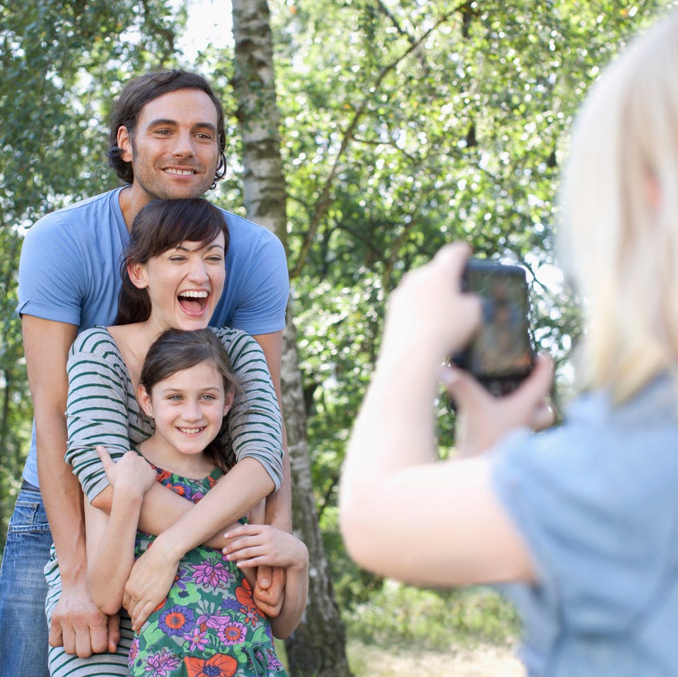 parents with daughter posing for photograph taken by another daughter